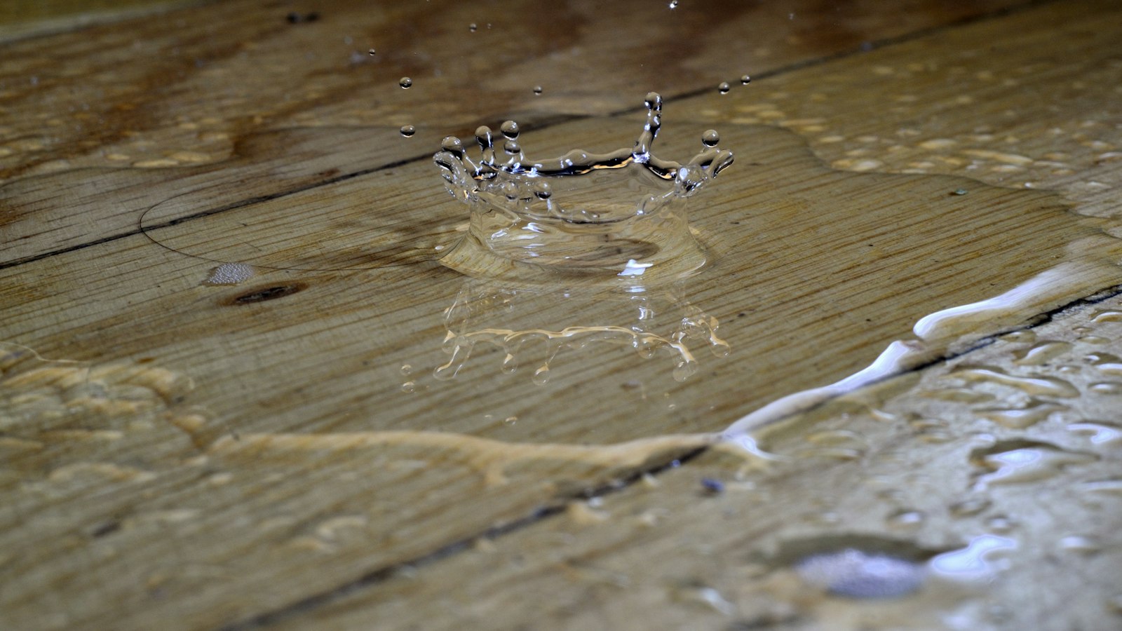 Water pooling and splashing on a wooden floor